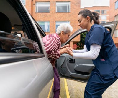 Home caregiver helping a senior woman get out of a car â assisted living concepts